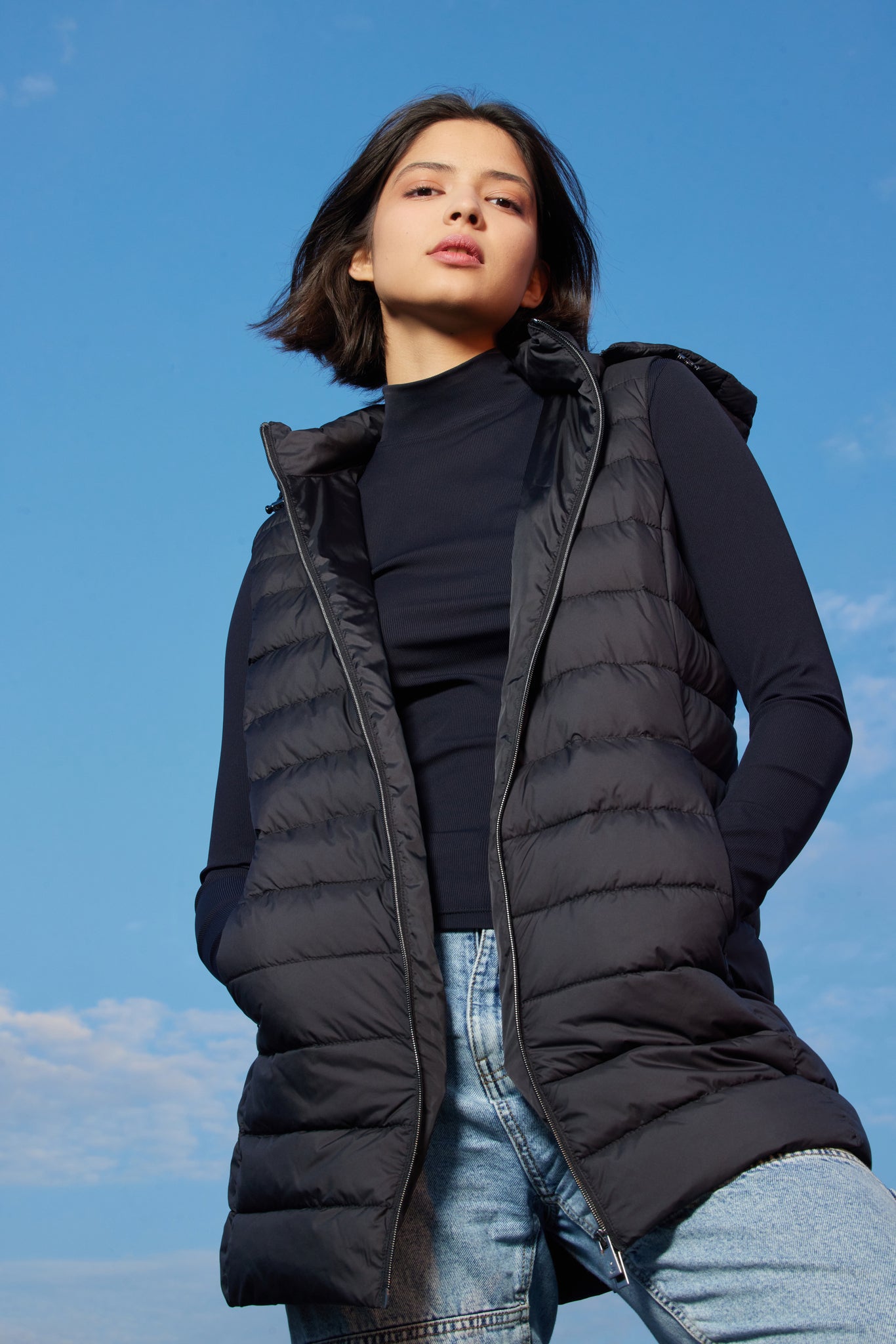 Vestă neagră damă Madzerini, matlasată, cu glugă și fermoar, detaliu modern casual.